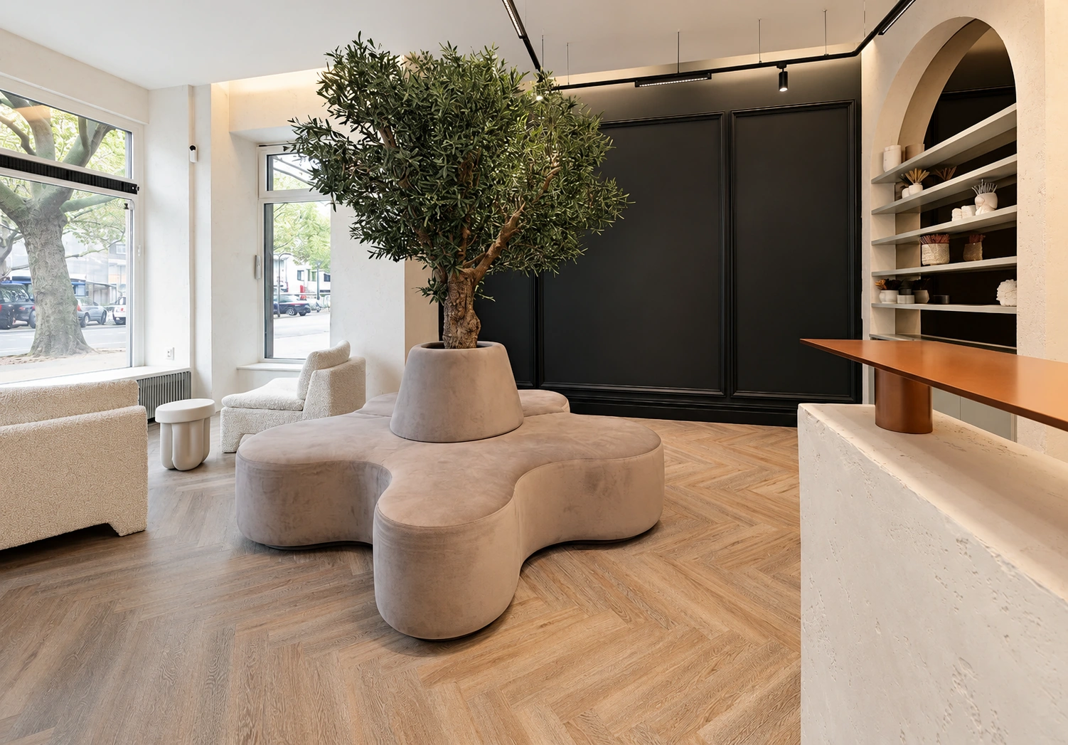 Lichtdurchflutete Lounge mit Olivenbaum, organischer Sitzbank und großen Fenstern