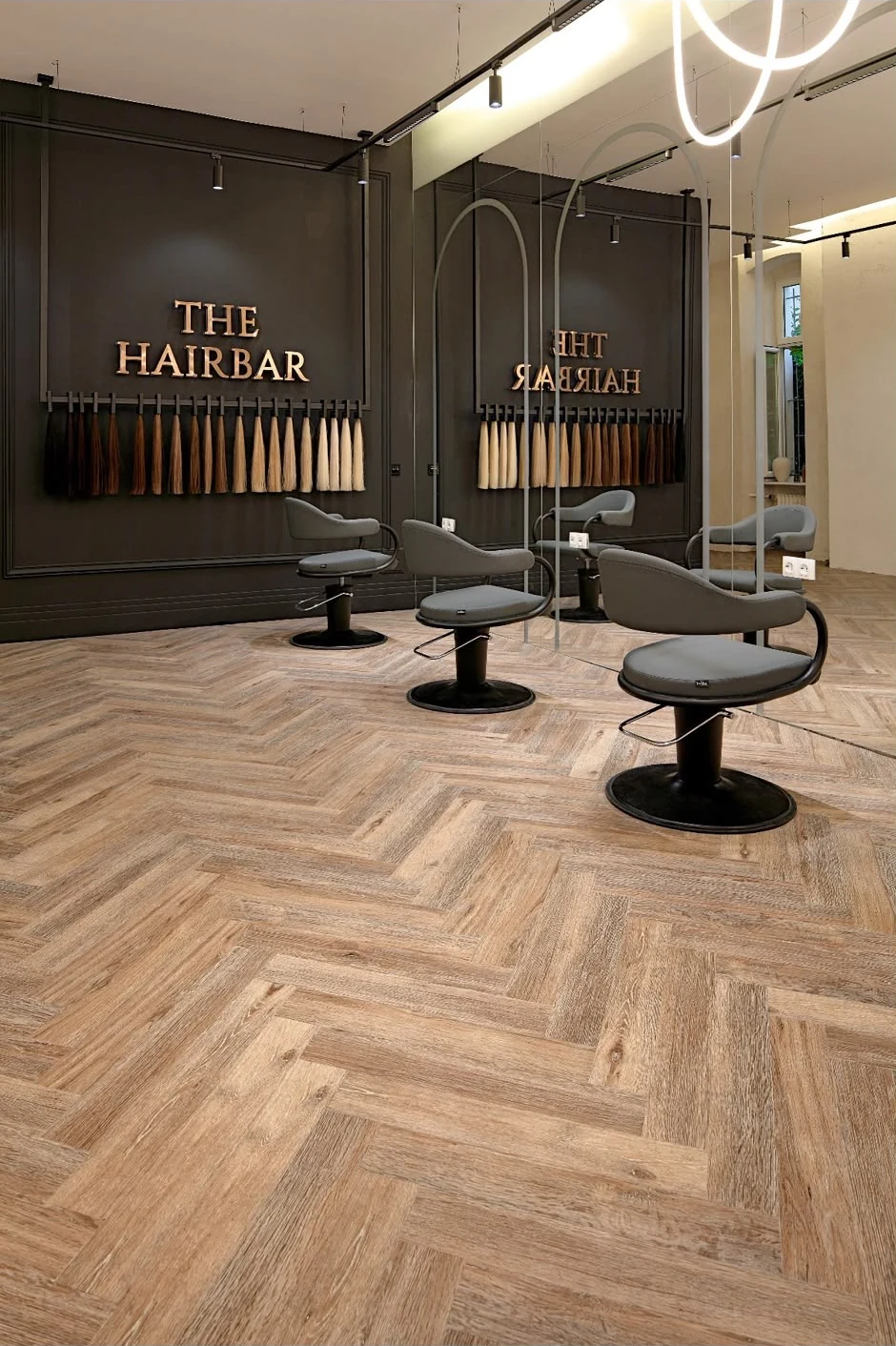 The Hairbar mit dunkler Wand, bronzenem Schriftzug, Haarfarbmustern und Spiegelplätzen