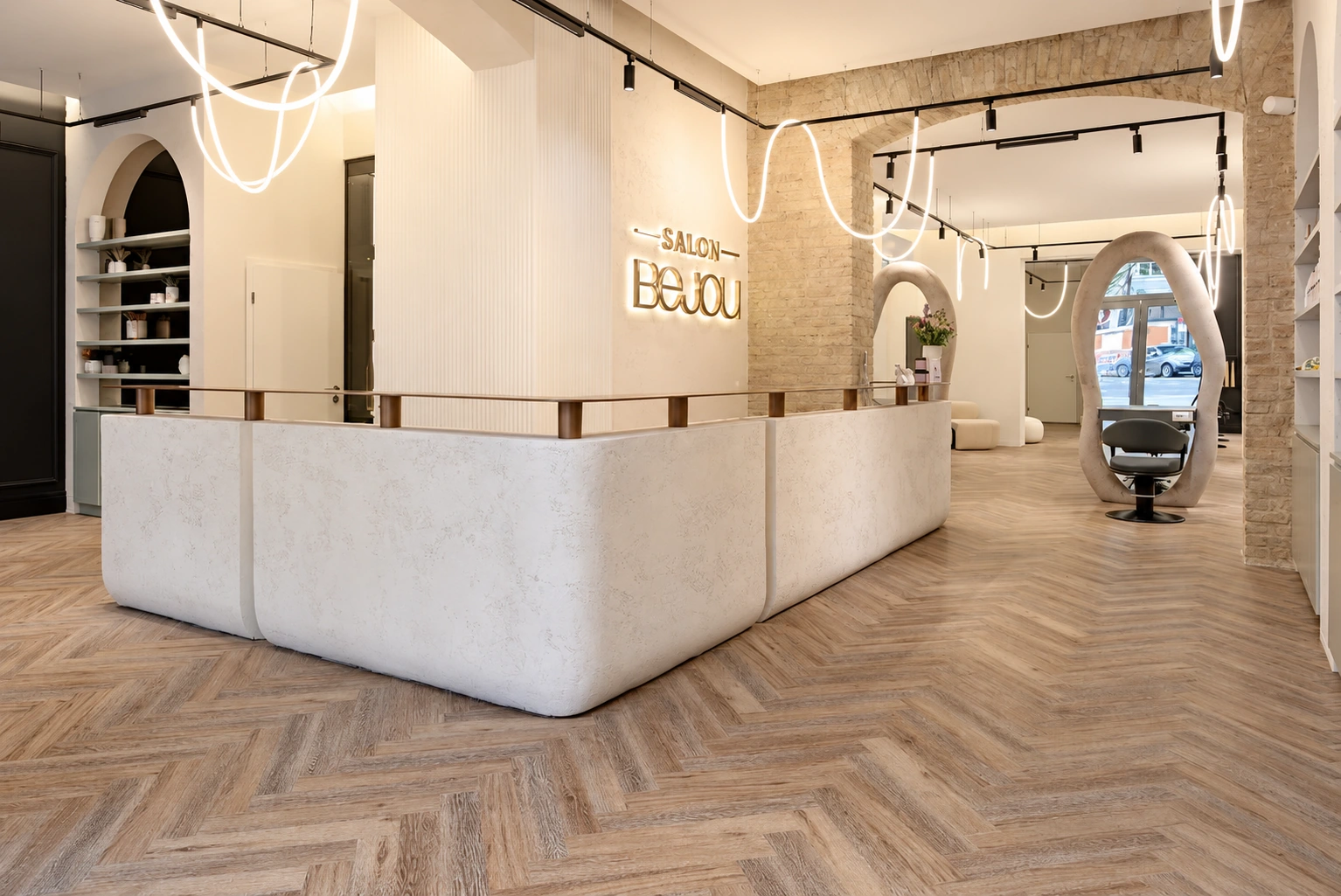 Heller Empfang von Salon Bejou mit bronzenem Schriftzug, Naturstein und geschwungenen Deckenleuchten